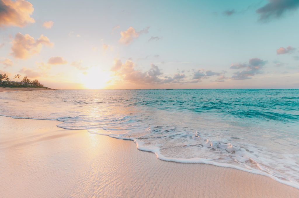 A wide sandy beach under a warm sunset sky