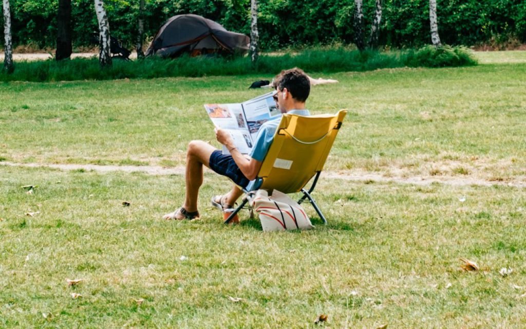 Woman reading a book on the grass in a city park