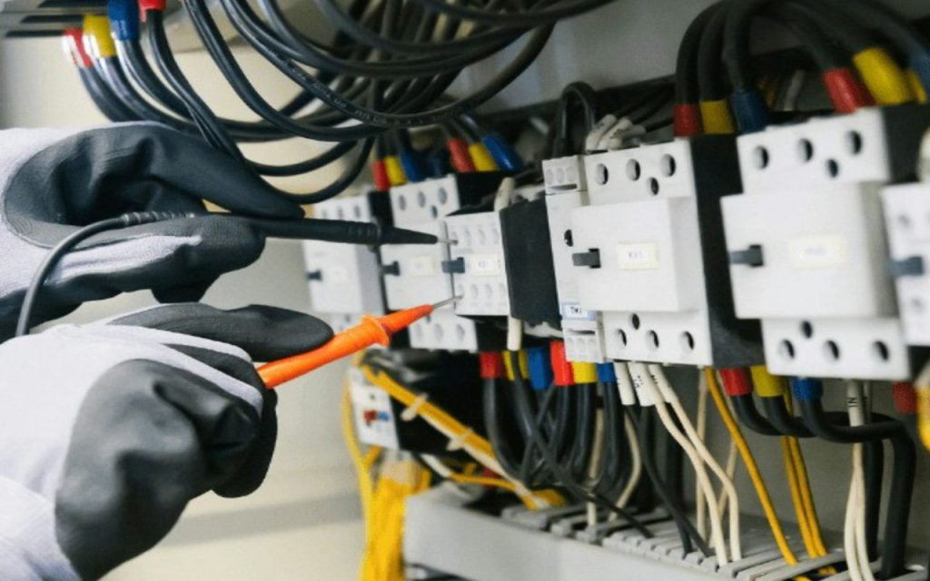 A hand switching a breaker in an electrical panel
