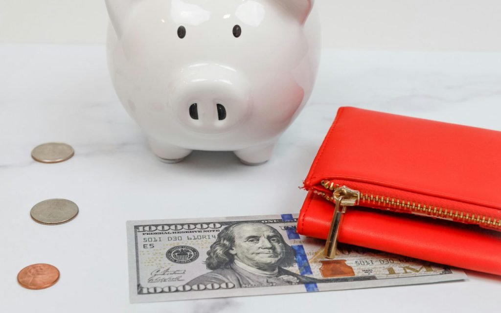 A piggy bank sitting next to a leather wallet