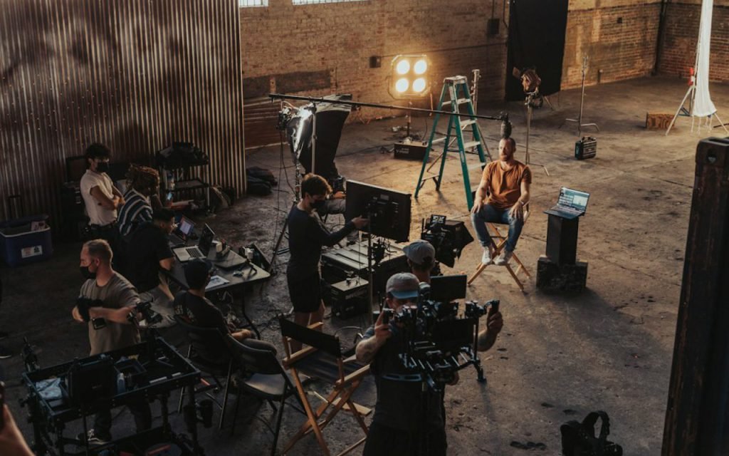 A small film crew setting up a camera and lights on a set