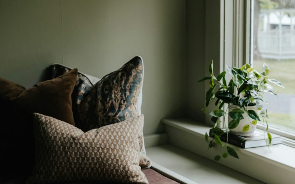 A cozy reading nook beside a window with cushions and books
