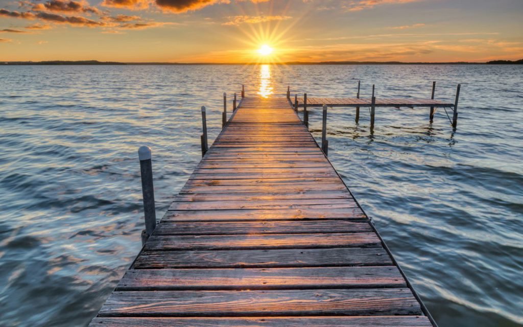 A wooden dock stretching into a calm lake at sunset