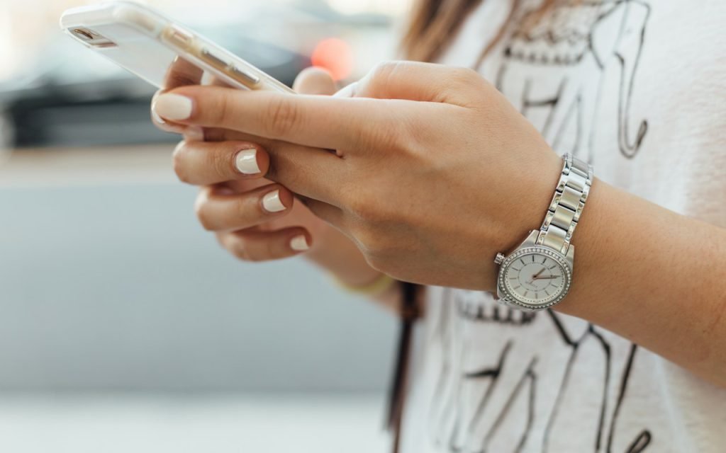 Hands holding a smartphone while scrolling a feed