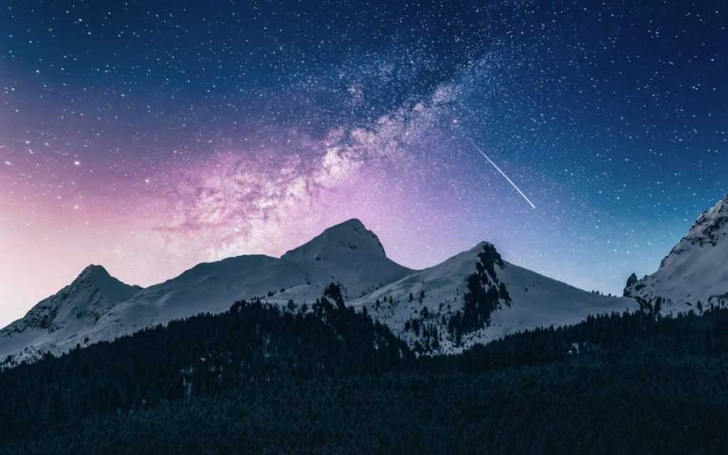The Milky Way arching over dark mountain peaks