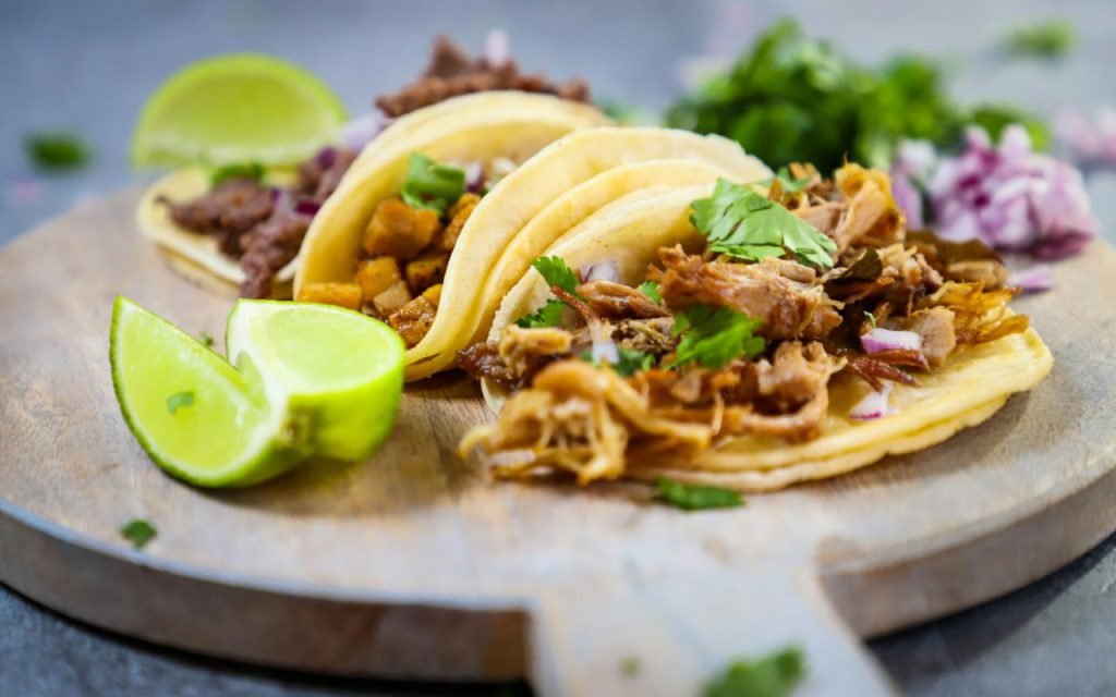 Tacos and fresh lime wedges on a wooden board