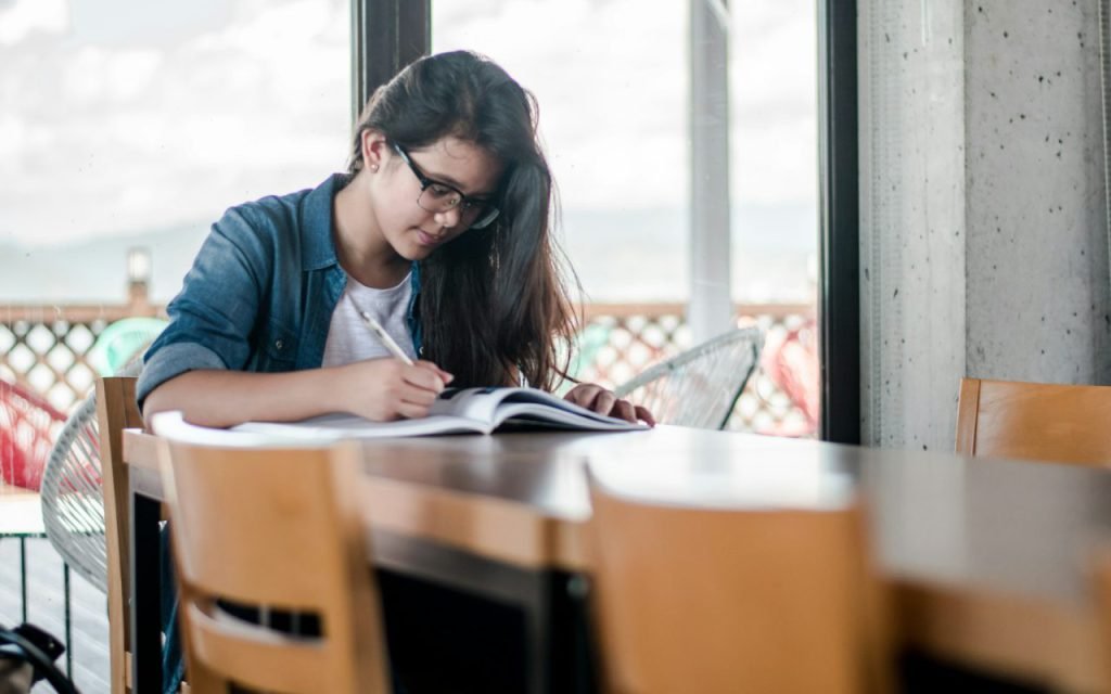 A teenager studying at a desk with books and notes